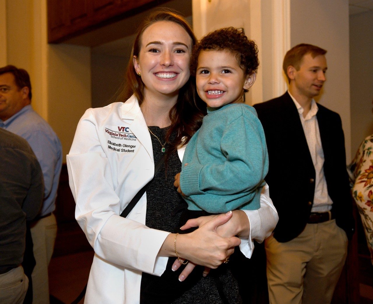 Liz Gienger wears her new white coat while holding her son, Elijah, at the VTCSOM White Coat Ceremony reception. Photos by Natalee Waters for Virginia Tech.