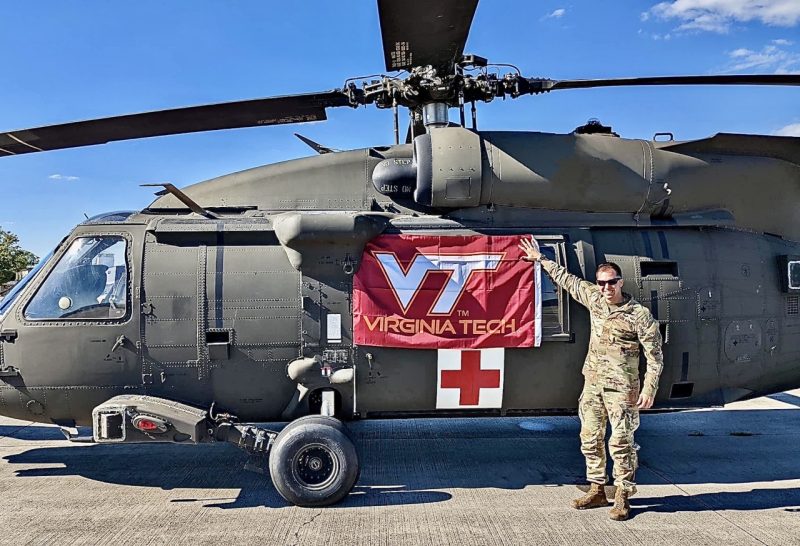 Maj. Travis Taggart holds a Virginia Tech flag against his helicopter. 
