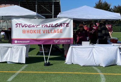 Check in area for Student Tailgate, volunteers at tables under a tent with an event banner