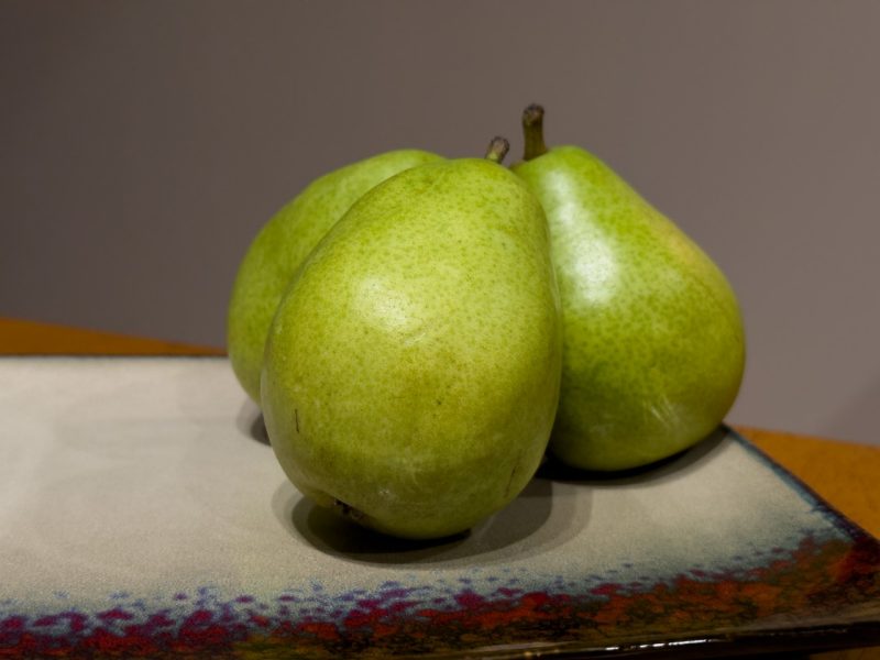 Green pears on a tan plate.