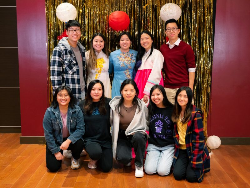 Ten members of the Asian American Student Union pose in front of a gold background at the 2022 Lunar New Year celebration. They are posed in two rows with five standing in the back and five kneeling in front. 
