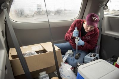 A Virginia Tech student works in the back of a van collecting water samples. 