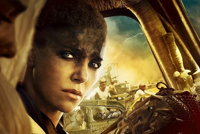 Furiosa sits at the wheel of her war rig as War Boys outside her window try to attack her.
