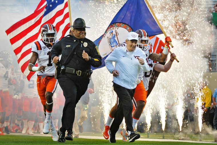 Police Capt. Vince Houston, at left, and former coach Frank Beamer run onto the football field.