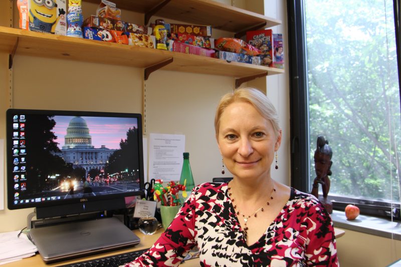 Woman standing in front of desk with shelves of processed foods in the background.