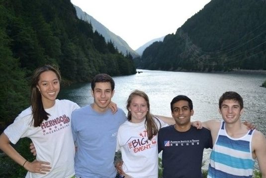 Five student interns in front of a wooded body of water.