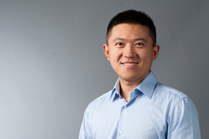 Headshot of Gang Wang in blue shirt against gray background