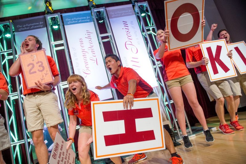 Orientation Leaders hold signs on stage as they hype up the crowd at Orientation