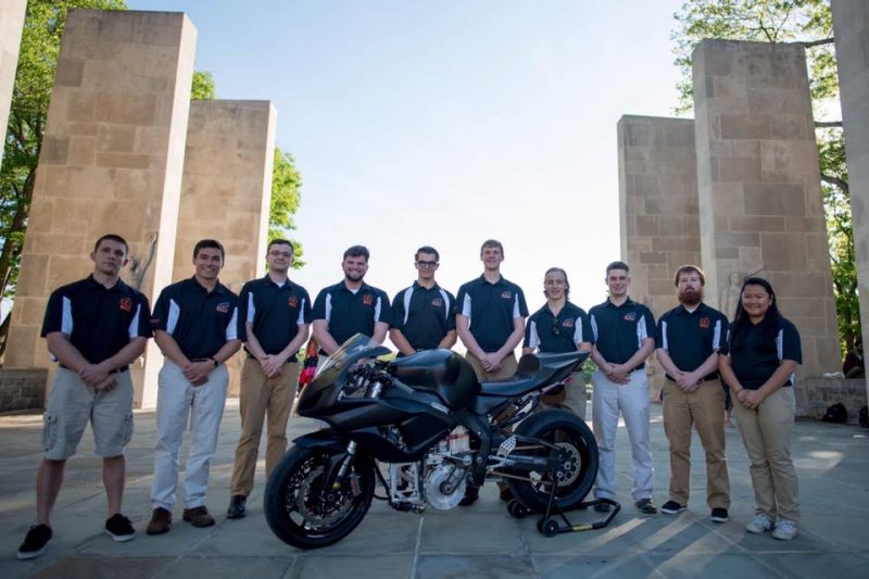 Students stand in front of Alumni Mall with the BOLT III motorcycle.