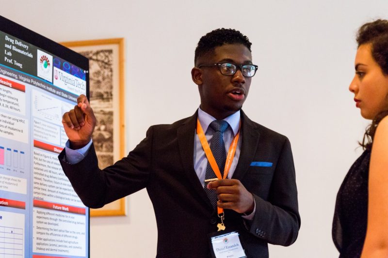 Daniel Essandoh (left), chemical engineering major at Virginia Tech, briefly explains his research project at the MAOP Summer Research Symposium.