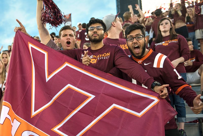 Hokie fans cheering and holding up a Virginia Tech flag