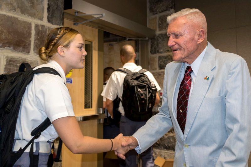 A female cadet, at left, shakes the hand of Col. Wesley L. Fox, at right.