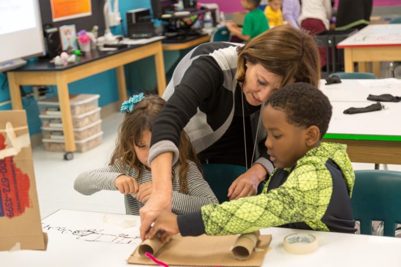 Cedar Point Elementary School STEAM Teacher Adair Solomon (center) helps a pair of first graders with their invention during an activity in the Tech Lab.