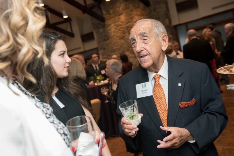 Howard Feiertag talks with two other guests at a reception.