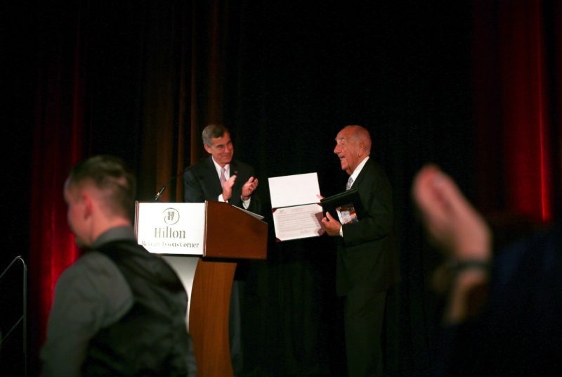 Charlie Phlegar, vice president for advancement, claps while Howard Feiertag holds the certificate  of his honorary lifetime membership in the Virginia Tech Alumni Association .