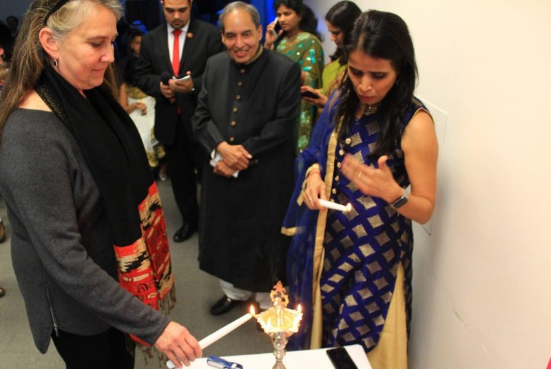 Business information technology professor Barbara Hoopes lights the lamp, which marks  the start of the event. To the right are hospitality and tourism management professor Mahmood Khan and MBA student Mala Lal.
