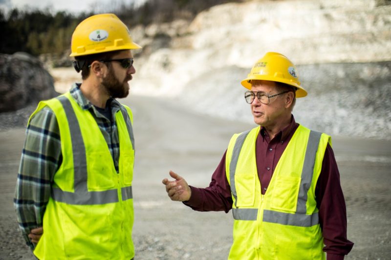 Two men chat while standing in a quarry.
