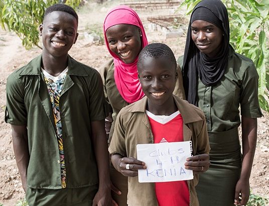 Two teenage boys and two teenage girls in Senegal pose for a picture.