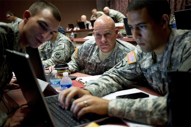 military specialists examine national security scenarios on a computer