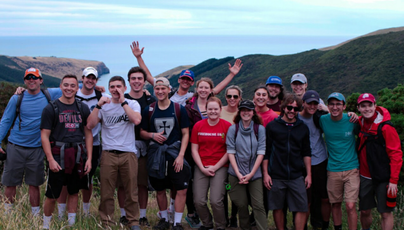 Photo of a group of students posing in New Zealand in front of a lush mountainous area.