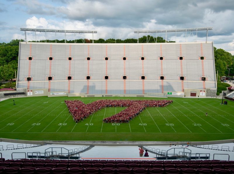 Photo of students in the shape of the VT athletic mark, in the middle of Lane Stadium