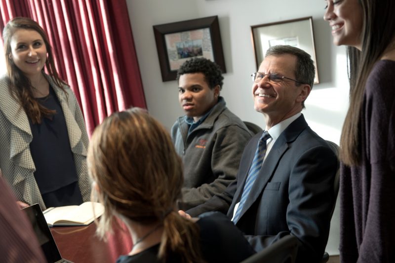 Dean Robert Sumichrast shares a light moment in his office with four students.