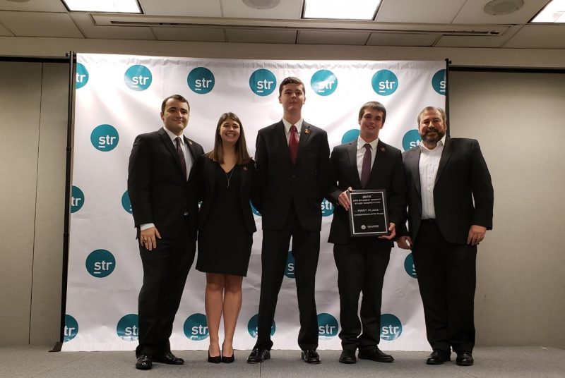 Hospitality and tourism management students Sean Koval, Bethany Ferraro, Austin Soule, and Lane Forney, who holds the prize-winning plaque, with Duane Vinson, vice president of STR, which provided the data for the competition and sponsored the event. 