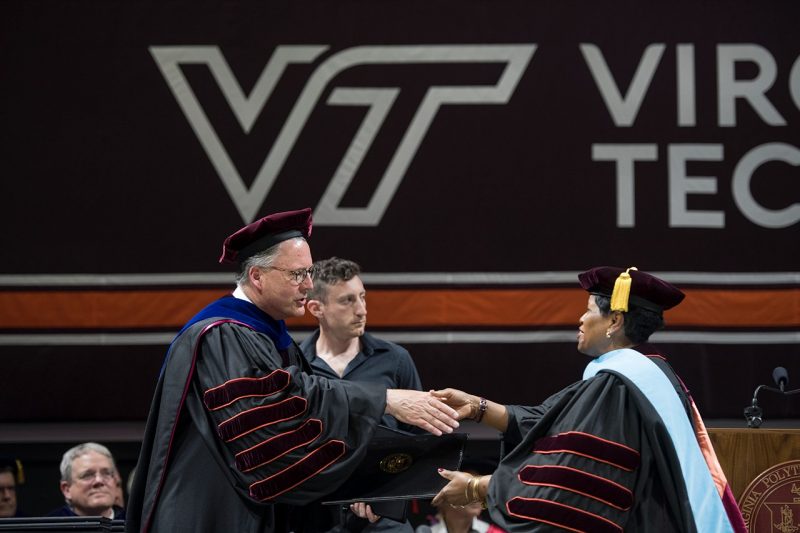 Virginia Tech President Tim Sands congratulates a newly robed Ph.D. recipient. 