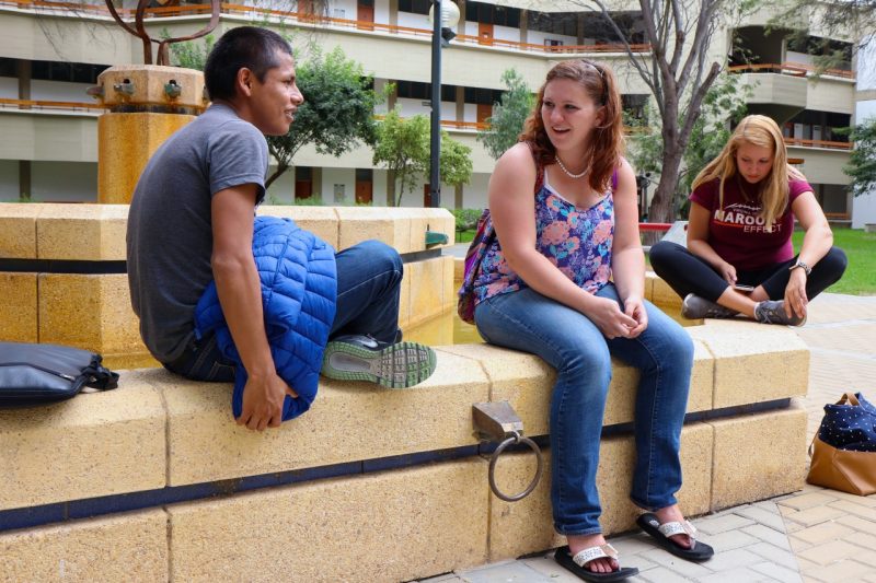 Three students sit on fountain wall on University of Piura campus