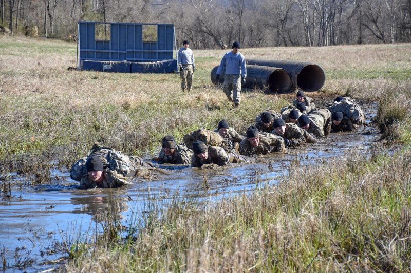 Cadets low-crawl through muddy water.