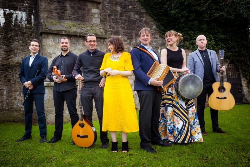 Irish ensemble Danu poses in front of a castle with their instruments.