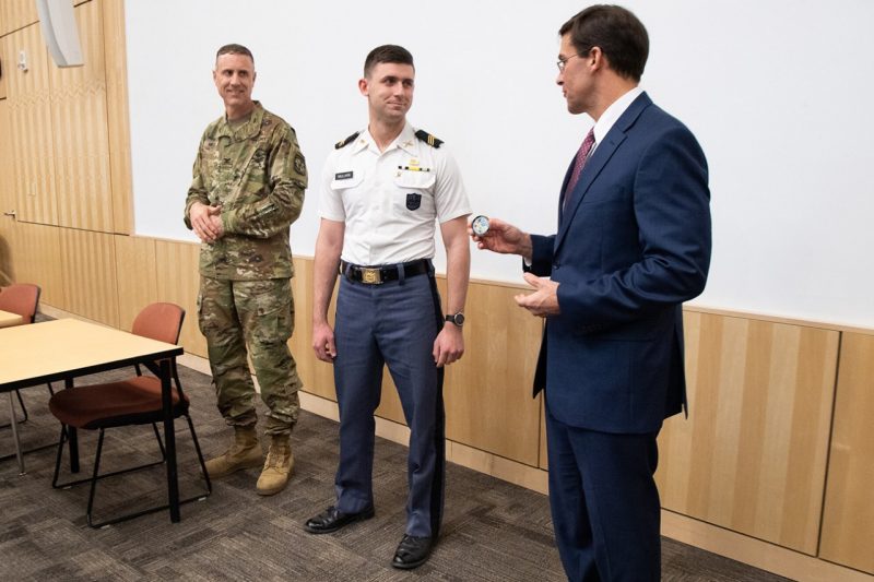 Col. Paul Mele, at left, watches as Cadet Patrick Millikin, at center, receives a coin from Secretary of the U.S. Army Mark T. Esper, at right.