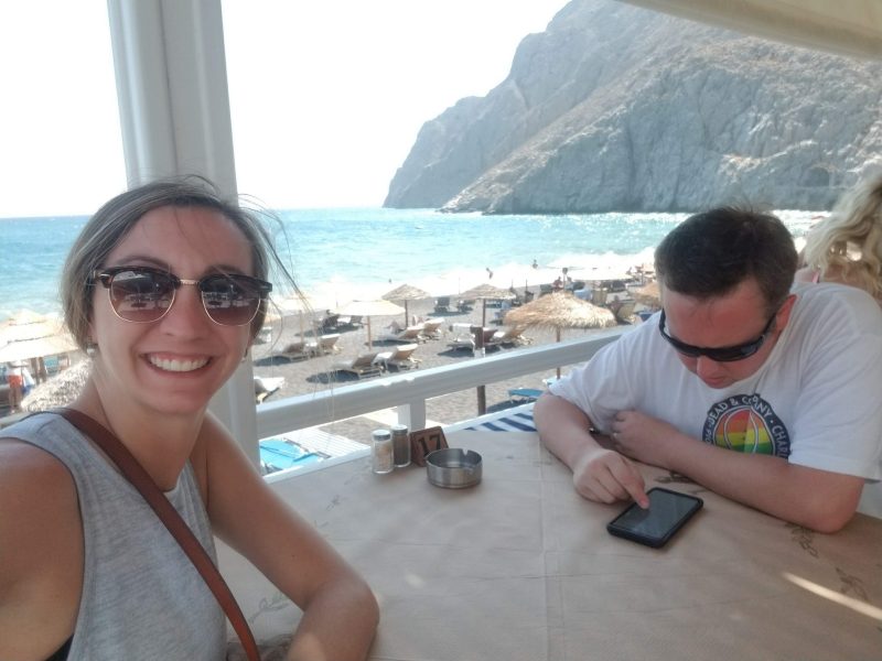 image of a couple on vacation, man checking work email on his phone 