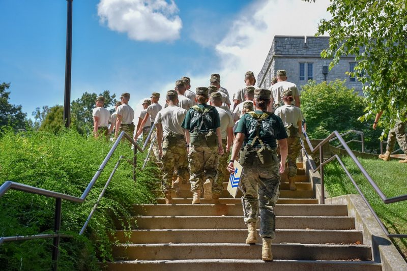 A line of first-year cadets march in formation up a set of steps.