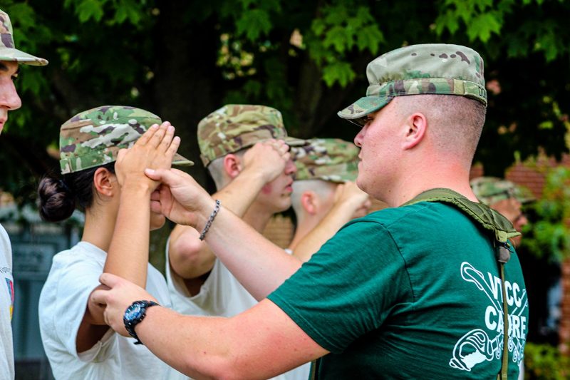 Cadet Stanley Dobis, at right, helps a new cadet learn to salute. 