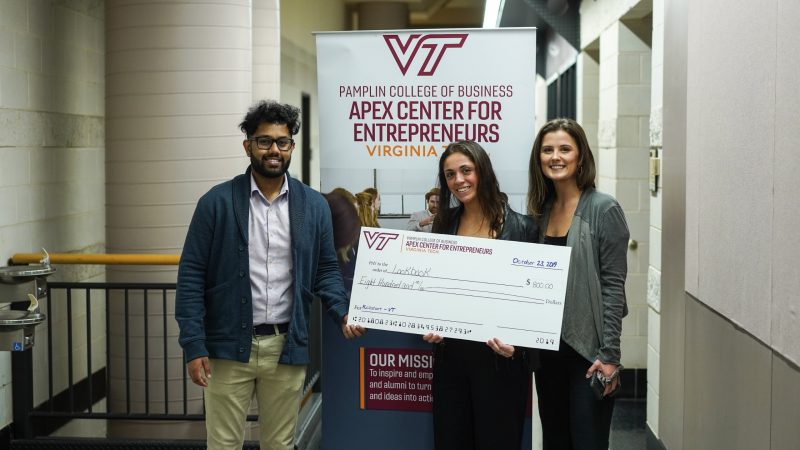Picture of three students holding a big check for $800 with a sign behind them that reads: Pamplin College of Business,  Apex Center for Entrepreneurs