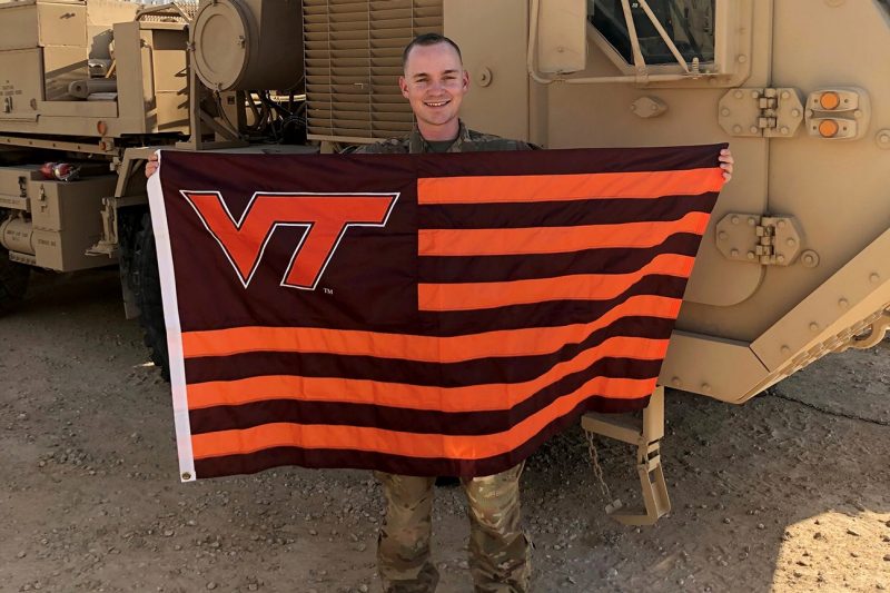 2nd Lt. William Breedlove  holds a Hokie flag while deployed to Iraq.