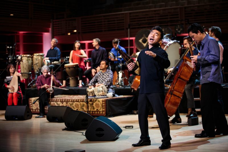 A group of musicians from the Silkroad Ensemble play their instruments onstage.
