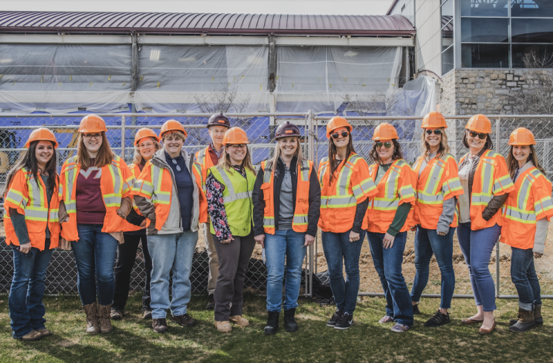 Women in Facilities and students interested in construction careers gathered together in front of the Student Athlete Performance Center renovation site.