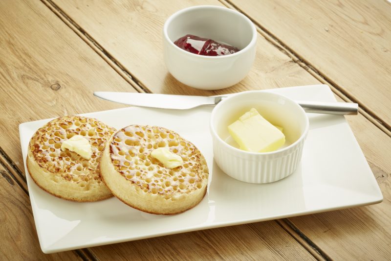 Sourdough crumpets sitting on a plate with butter and jelly