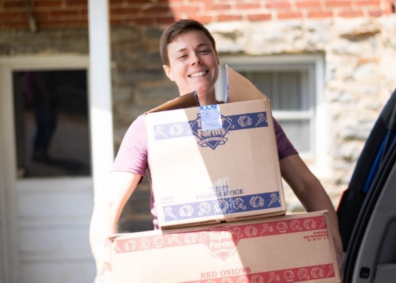 VT Engage team member Catherine Cortrupi carries boxes of food in the daylight. 