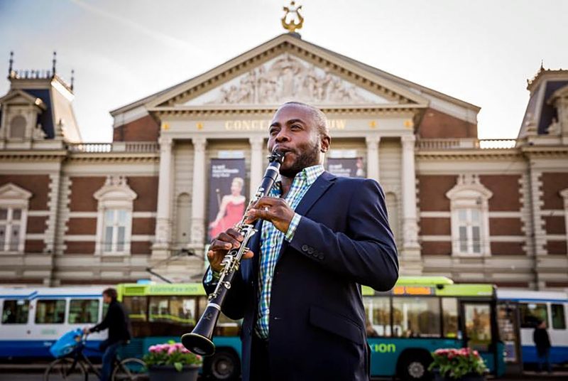 Musician Anthony McGill plays the clarinet outside of a performing arts hall.