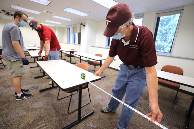 Gary Costello (right), associate registrar for classroom scheduling and governance at Virginia Tech, measures 6-feet distance between desks in a campus classroom. Costello, along with other university employees, are working to reconfigure classrooms throughout campus to meet physical distancing and health guidelines set by the Virginia Department of Health due to COVID-19. Photo by Ray Meese for Virginia Tech