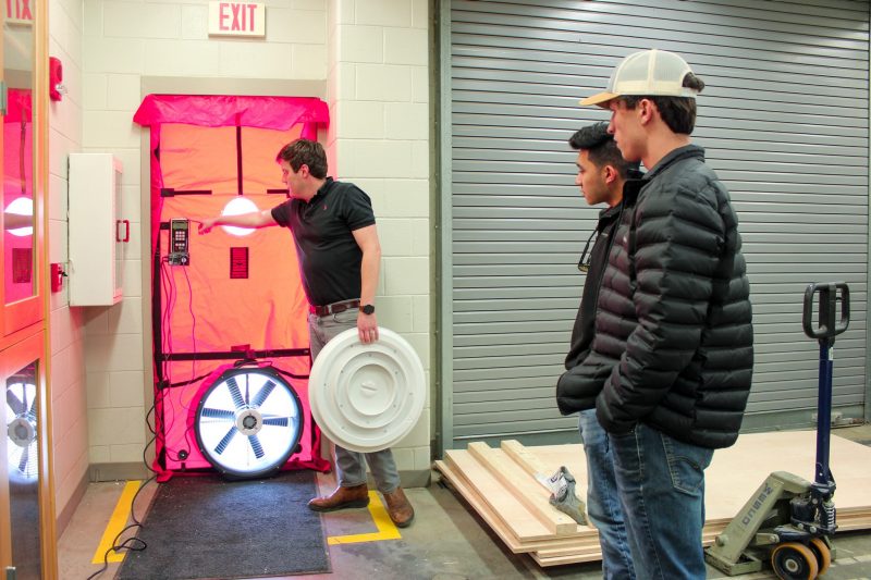 Assistant professor Philip Agee explains how a blower door measures airflow to students in the Myers-Lawson School of Construction