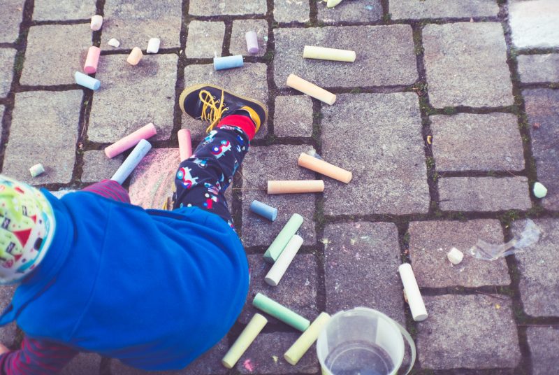 A child plays with sidewalk chalk.