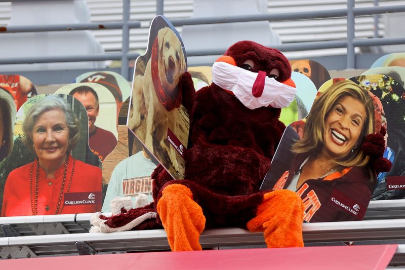 HokieBird holds two fan cutouts at Lane Stadium