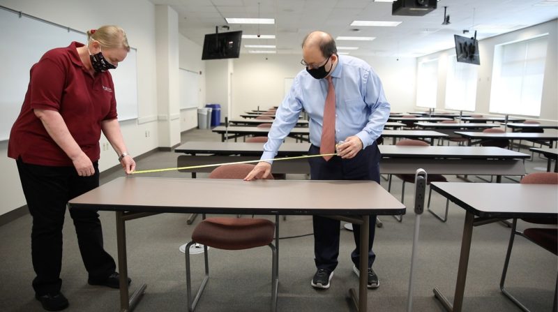 Kenneth Wong (right), director of the Northern Virginia Center and associate dean of the Graduate School, measures desks so that they are spaced at a 6-foot distance from others in a classroom in the Northern Virginia Center in Falls Church. Photo by Erin Williams for Virginia Tech.