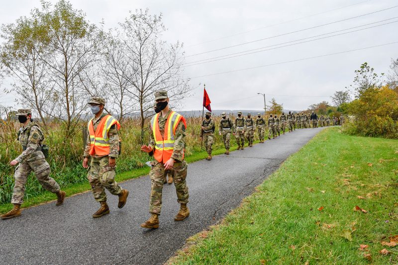 A line of cadets walks on a paved trail.