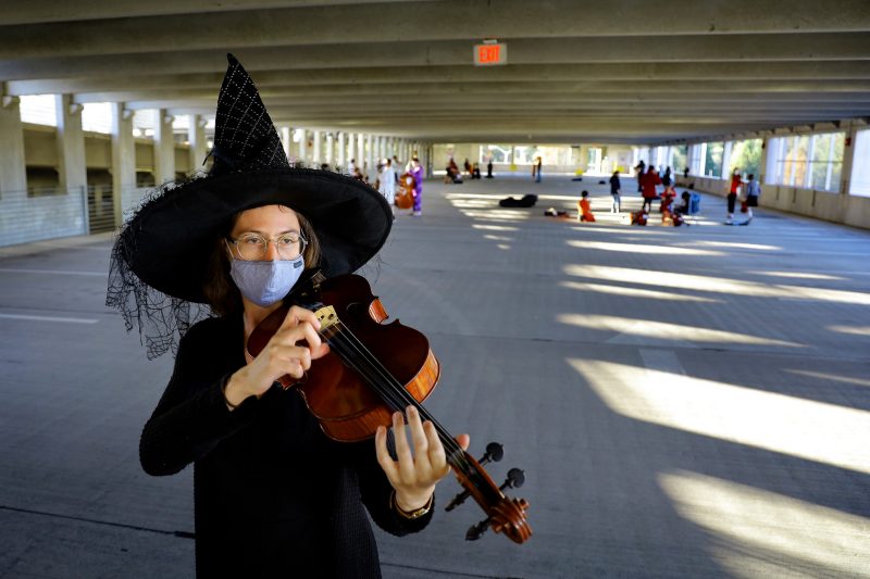 Dressed as a witch in celebration of Halloween, Molly Wilkens-Reed, director of the Virginia Tech String Project, leads music instruction in the Perry Street Parking Garage.