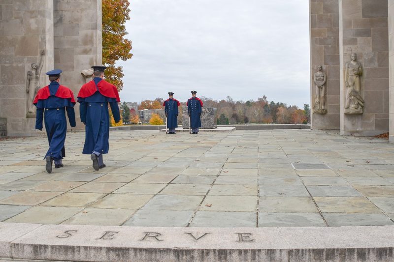 Two cadets in blue dress uniforms march forward to relieve two other cadets standing guard at the Pylons.